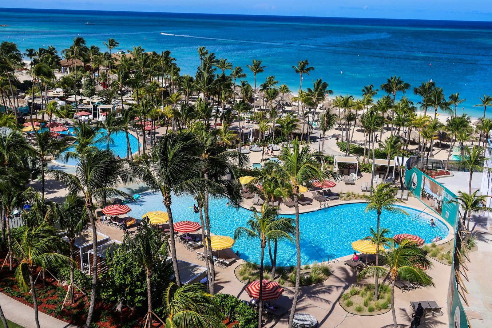Tropical oceanfront resort with pools and palm trees for a bright June wellness escape.