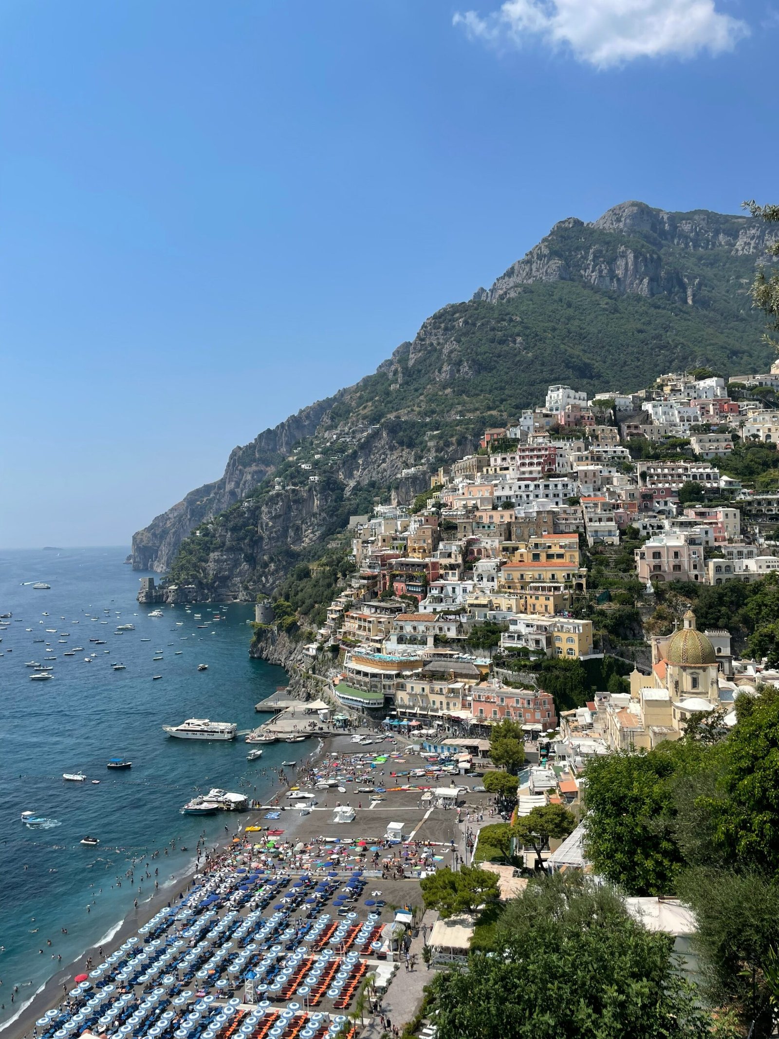Coastal view near Positano on the Amalfi Coast with sunlit rock formations and deep blue water.