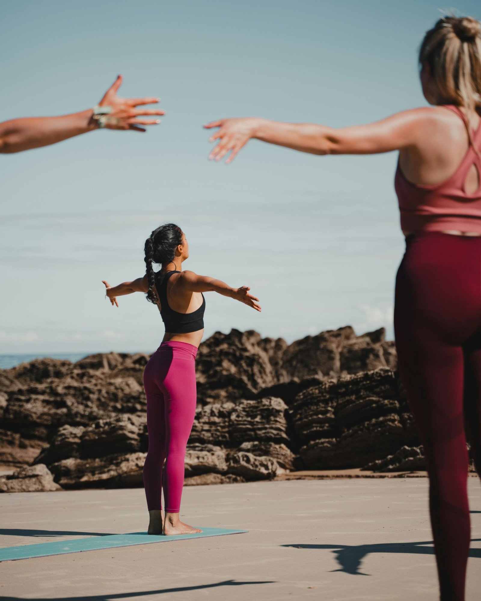 A yoga instructor leading a class on a sandy beach with rocky cliffs, illustrating the specialized expertise required to host a safe and professional outdoor yoga retreat.