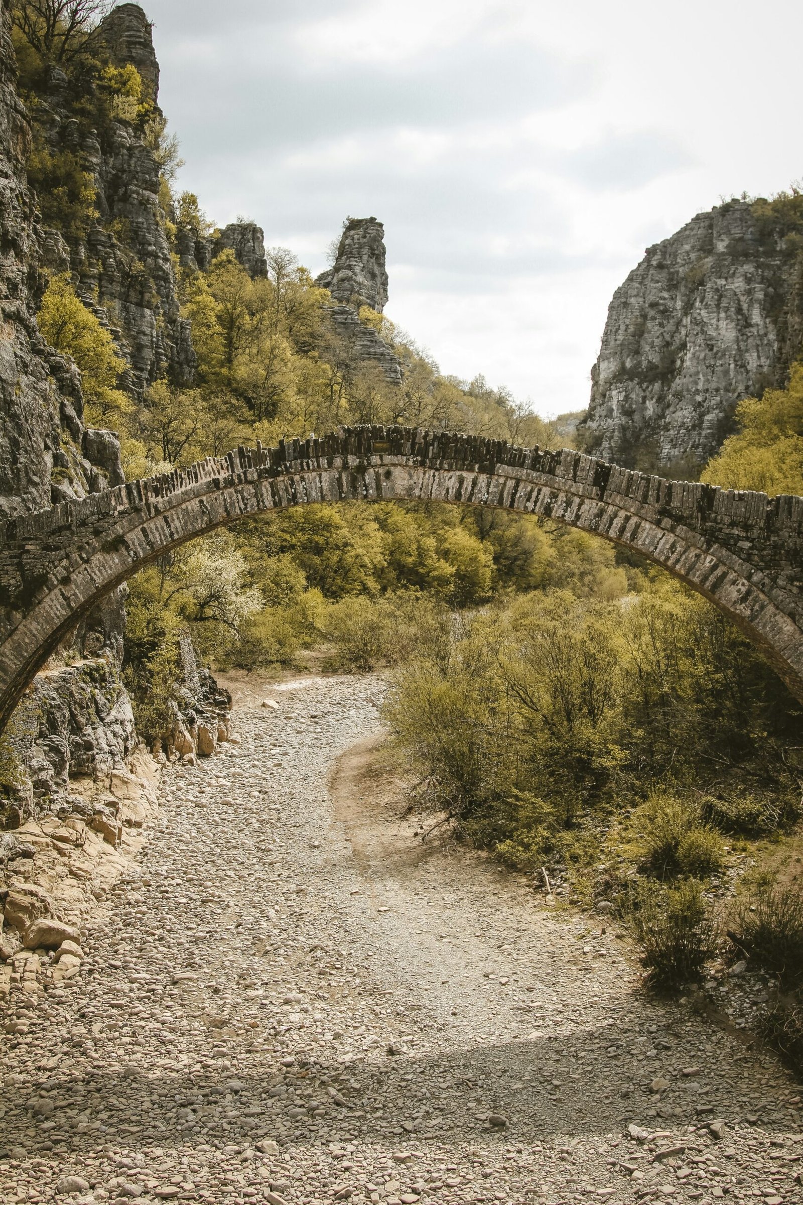 Stone bridge in Zagori surrounded by mountains, creating a secluded winter retreat feeling in northern Greece.