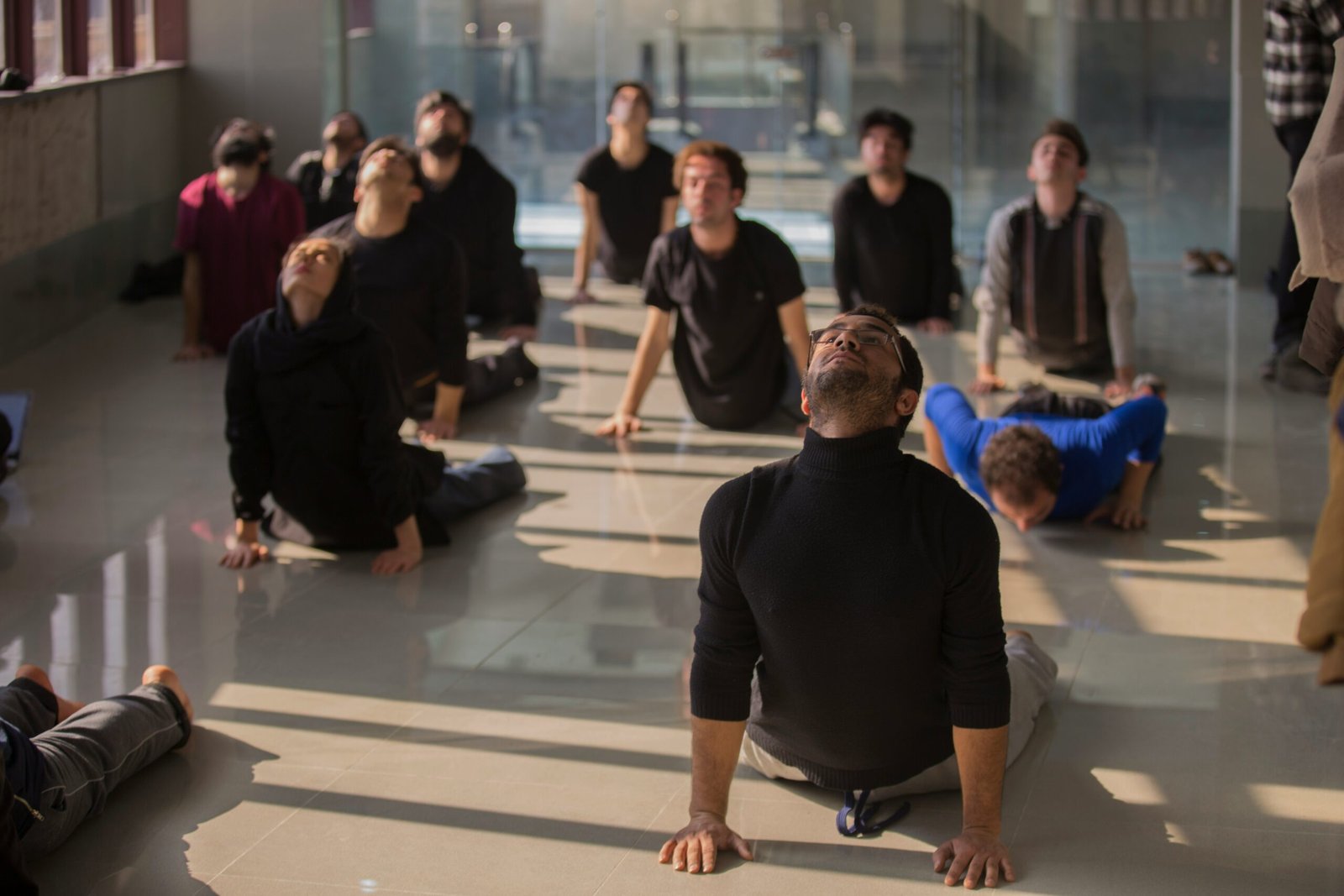 A diverse group of yoga students practicing cobra pose in a bright studio, illustrating the inclusive and professional guidance provided by a certified yoga instructor.