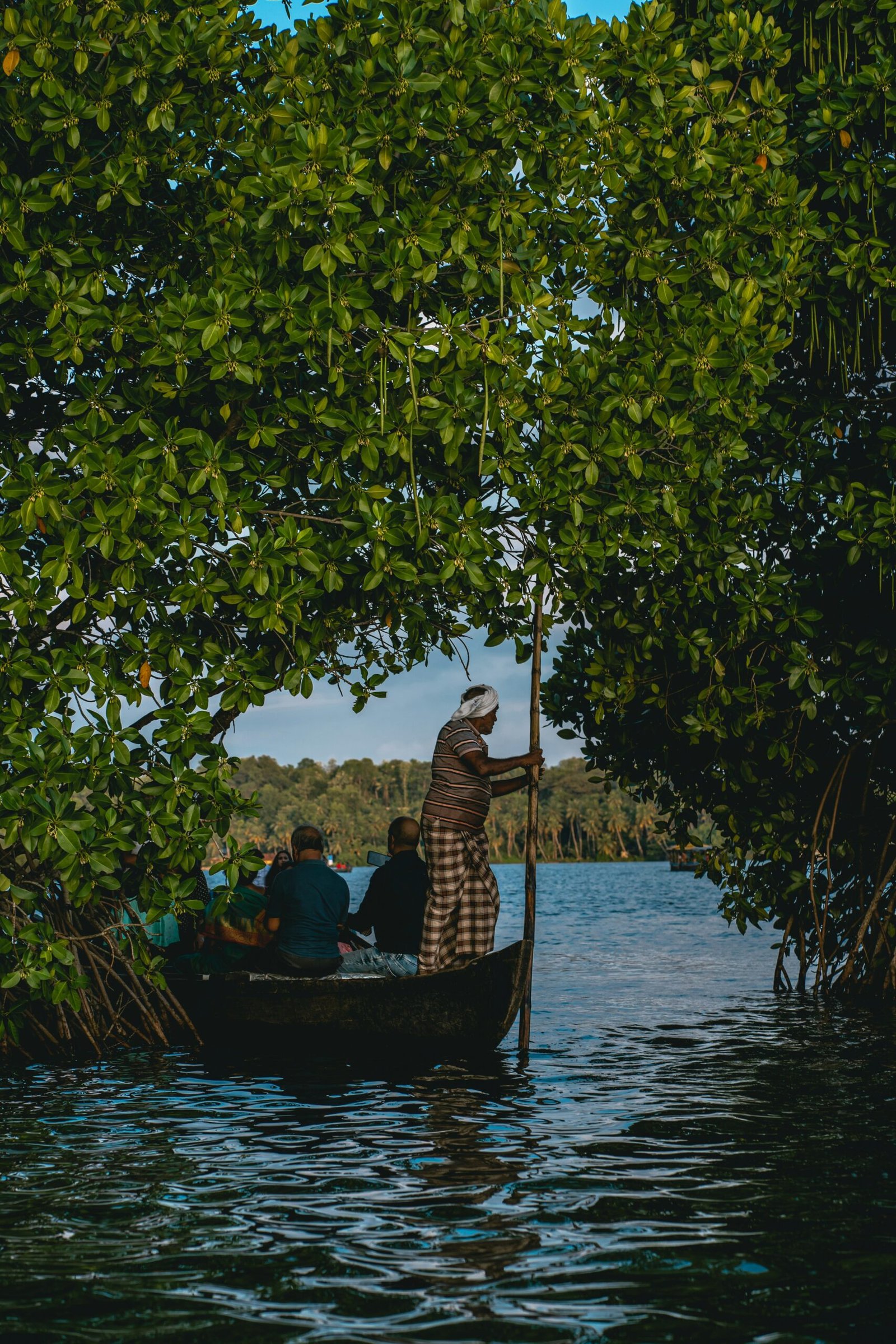Wooden boat gliding through the Kerala backwaters at sunset on Munroe Island, matching the slow and calming atmosphere of a retreat escape.