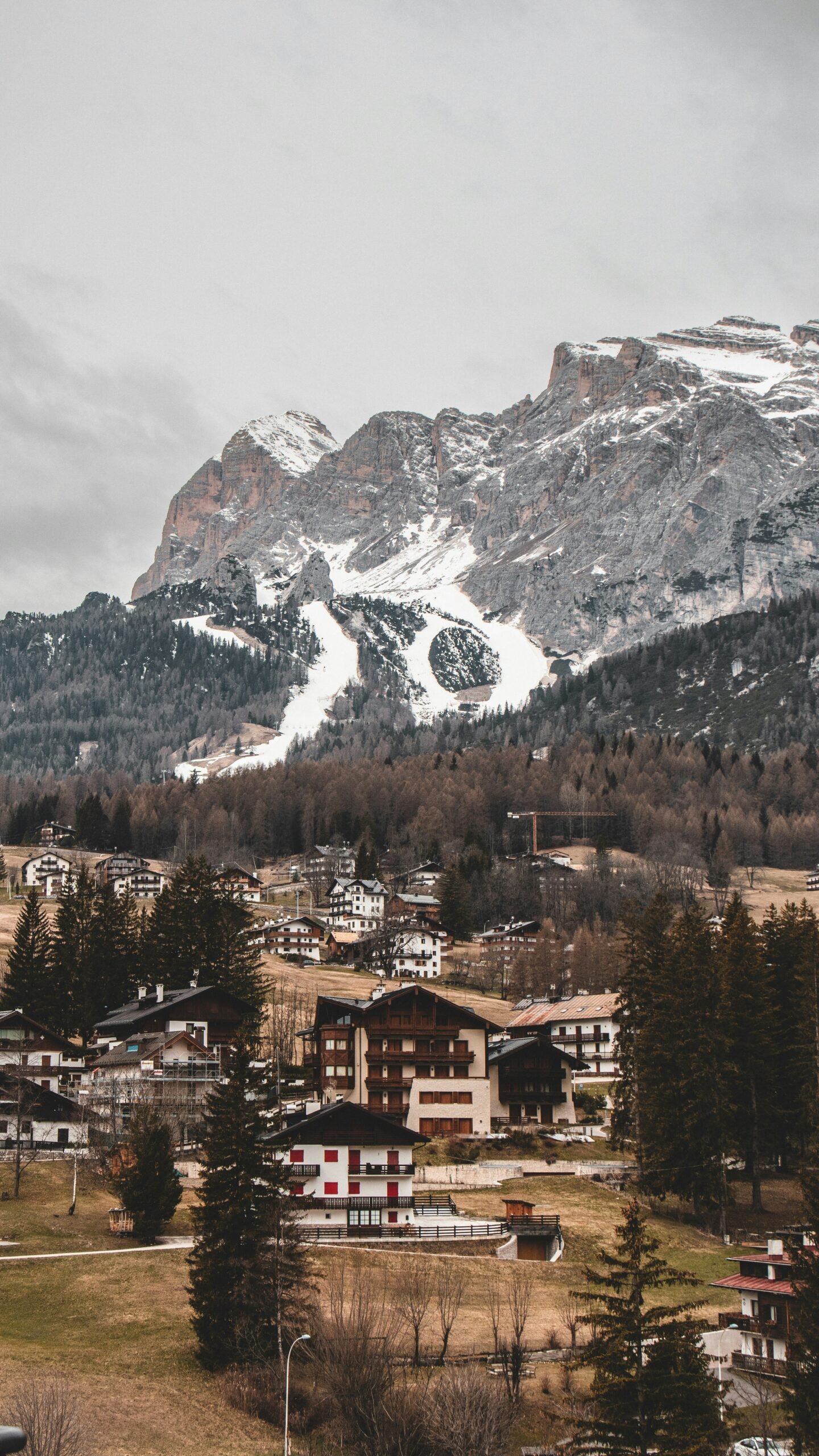 Snow-covered village in the Dolomites with dramatic peaks rising behind the rooftops.
