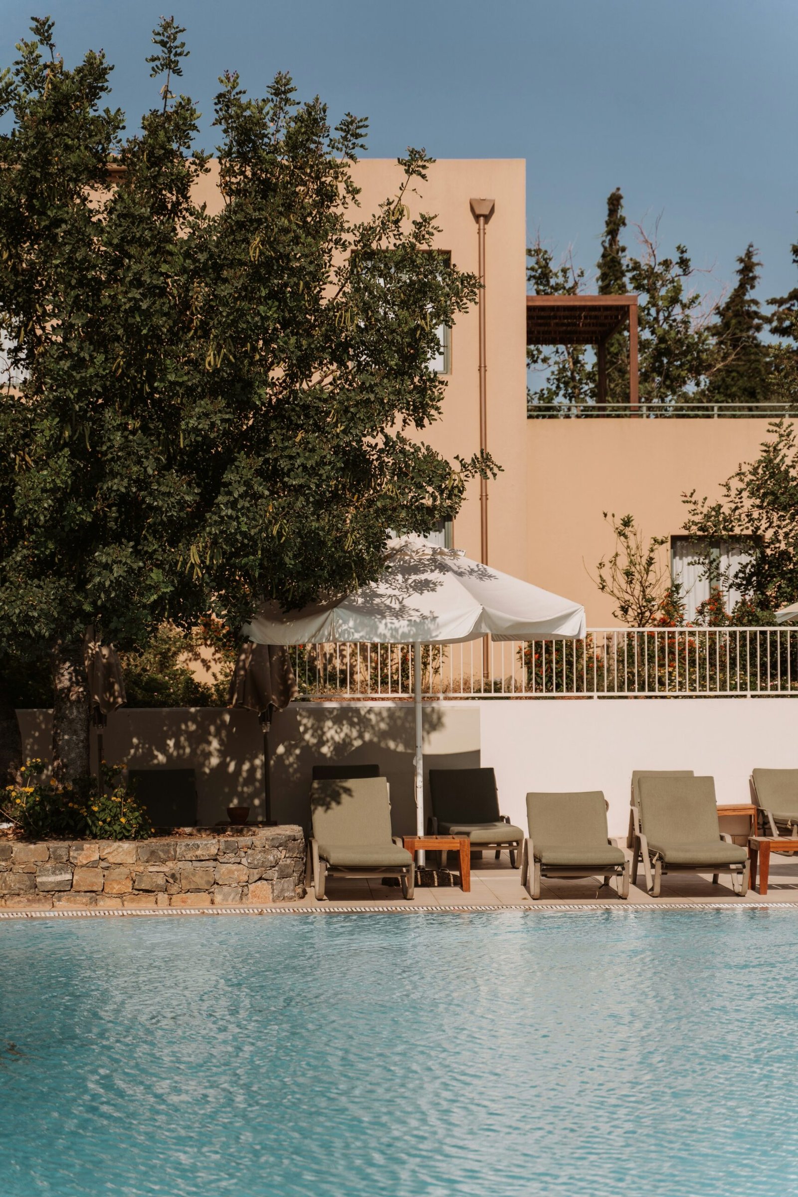 Poolside chairs and umbrella beside a resort building, suited to a calm retreat stay with space to unwind.