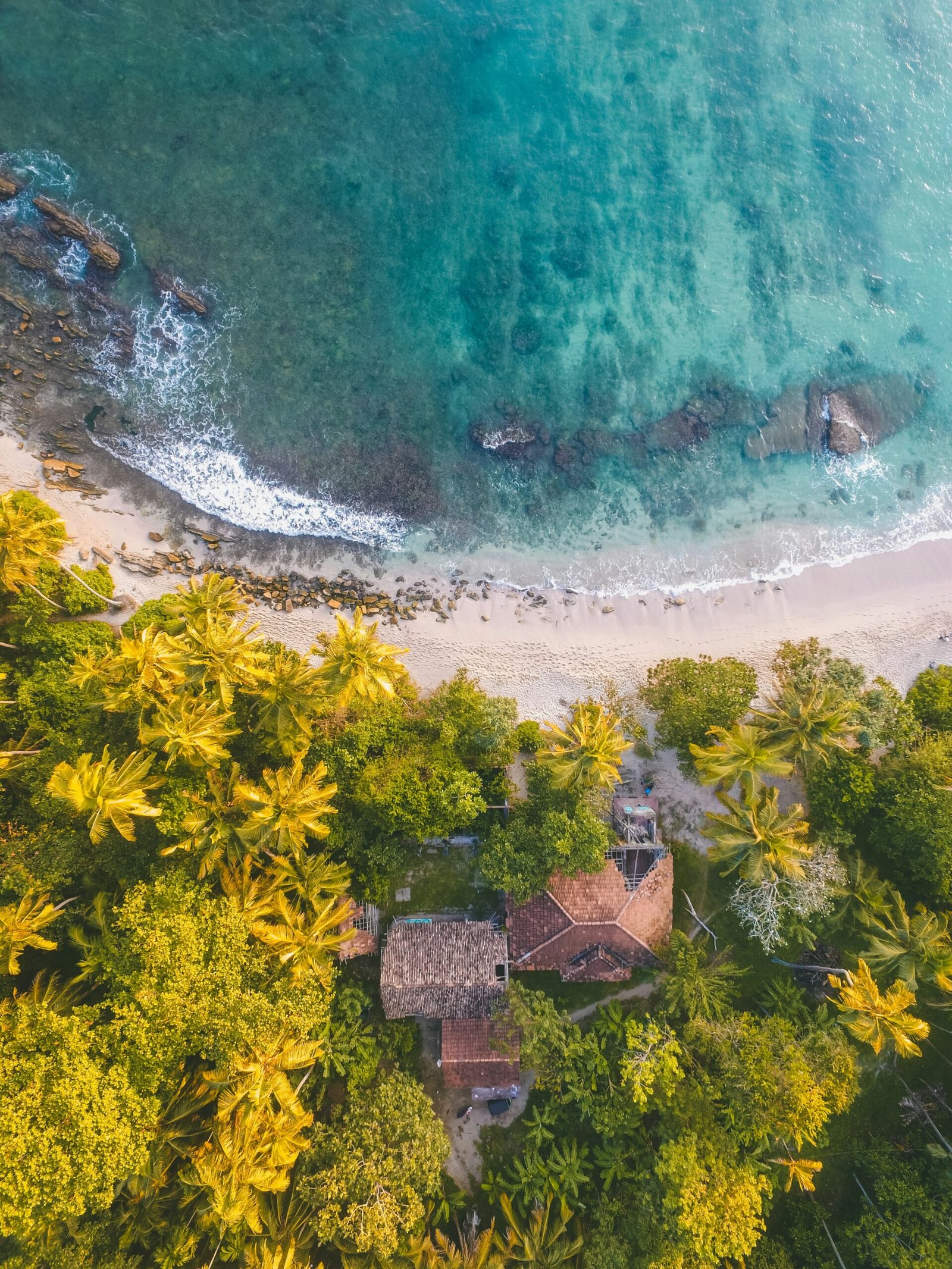 Aerial view of a Sri Lanka shoreline with turquoise water and villas, bringing a calm and expansive feel to a coastal yoga retreat.