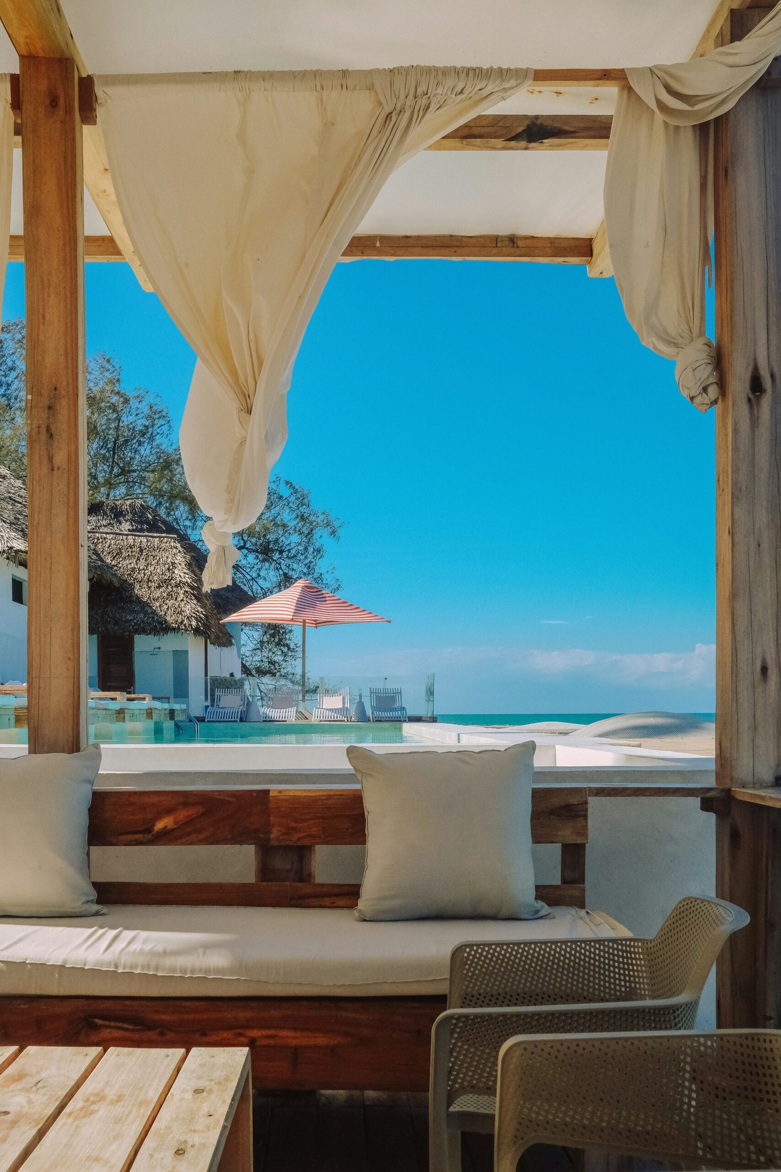 Tropical beachfront resort with a pool and lounge seating area overlooking the coast.