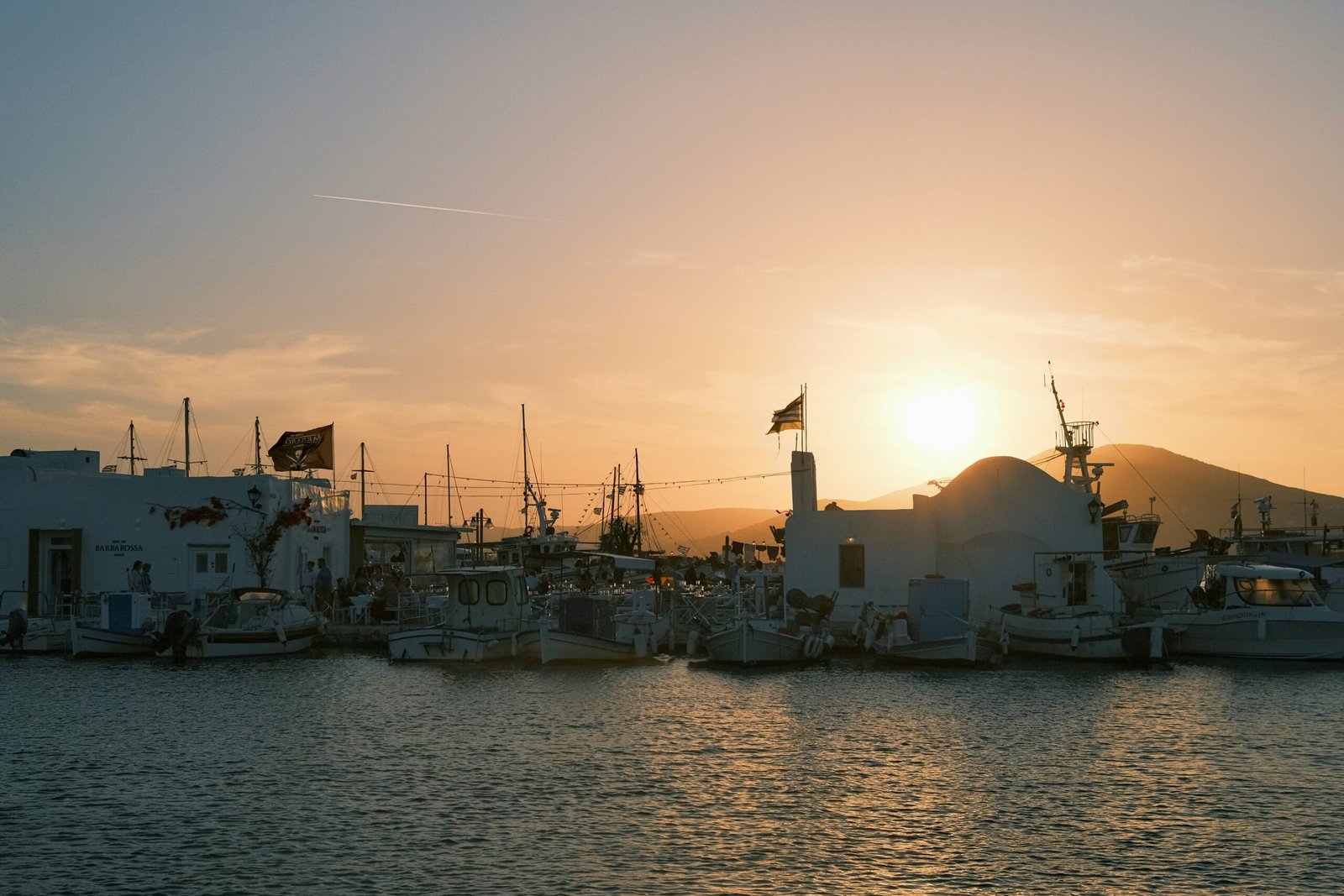 Sunset harbor in Naousa, Paros, reflecting the golden light and gentle transition of a September retreat in Greece.