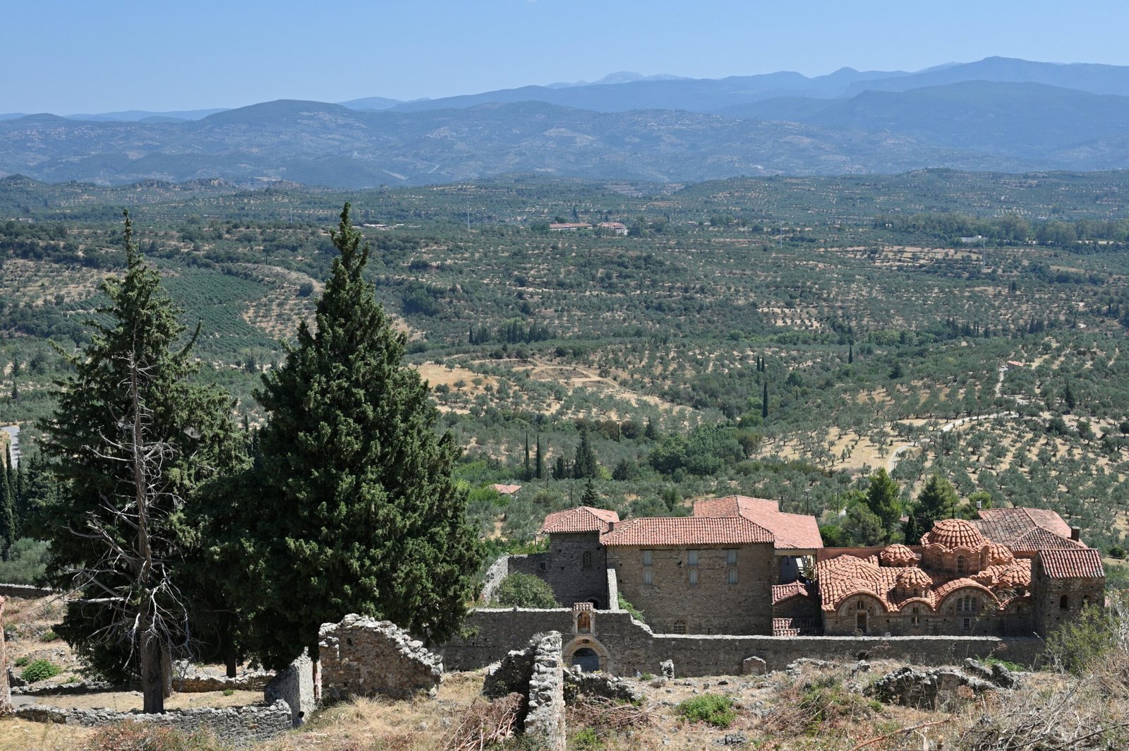 Monastery ruins above olive groves near Sparti, Greece, creating a grounded autumn retreat landscape.