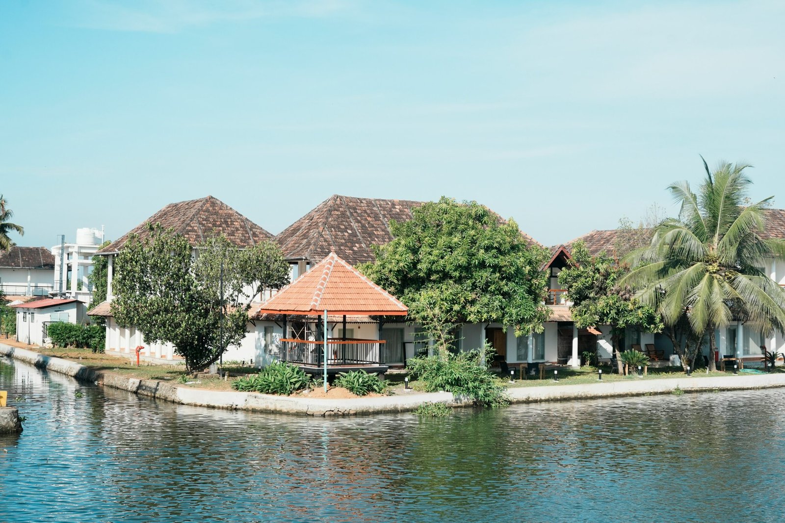 Tropical retreat buildings beside a serene Kerala waterway surrounded by palms
