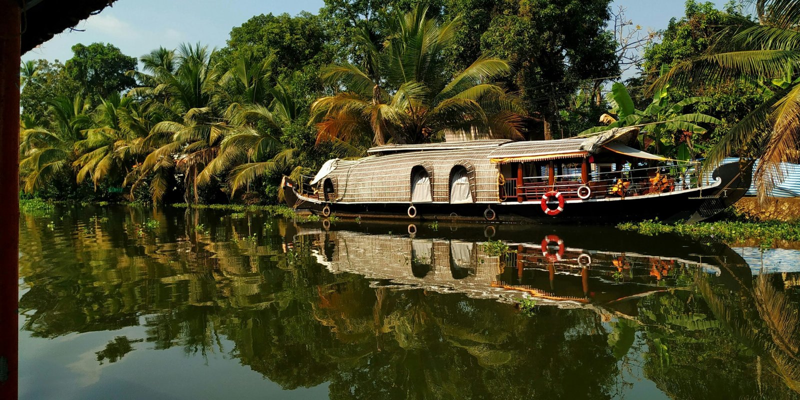 Houseboat drifting through Kumarakom backwaters in Kerala, matching the calm and rejuvenating atmosphere of an Ayurveda retreat in September.