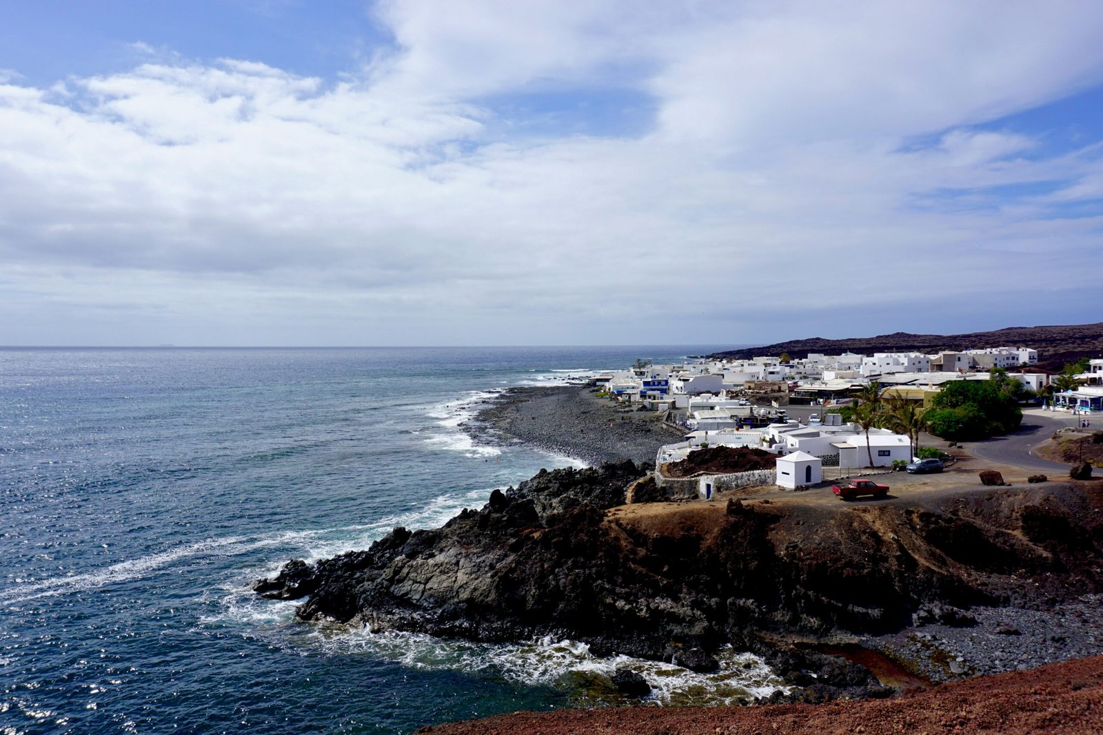 Coastal village and black-sand shoreline in the Canary Islands, Spain, under warm May sunshine