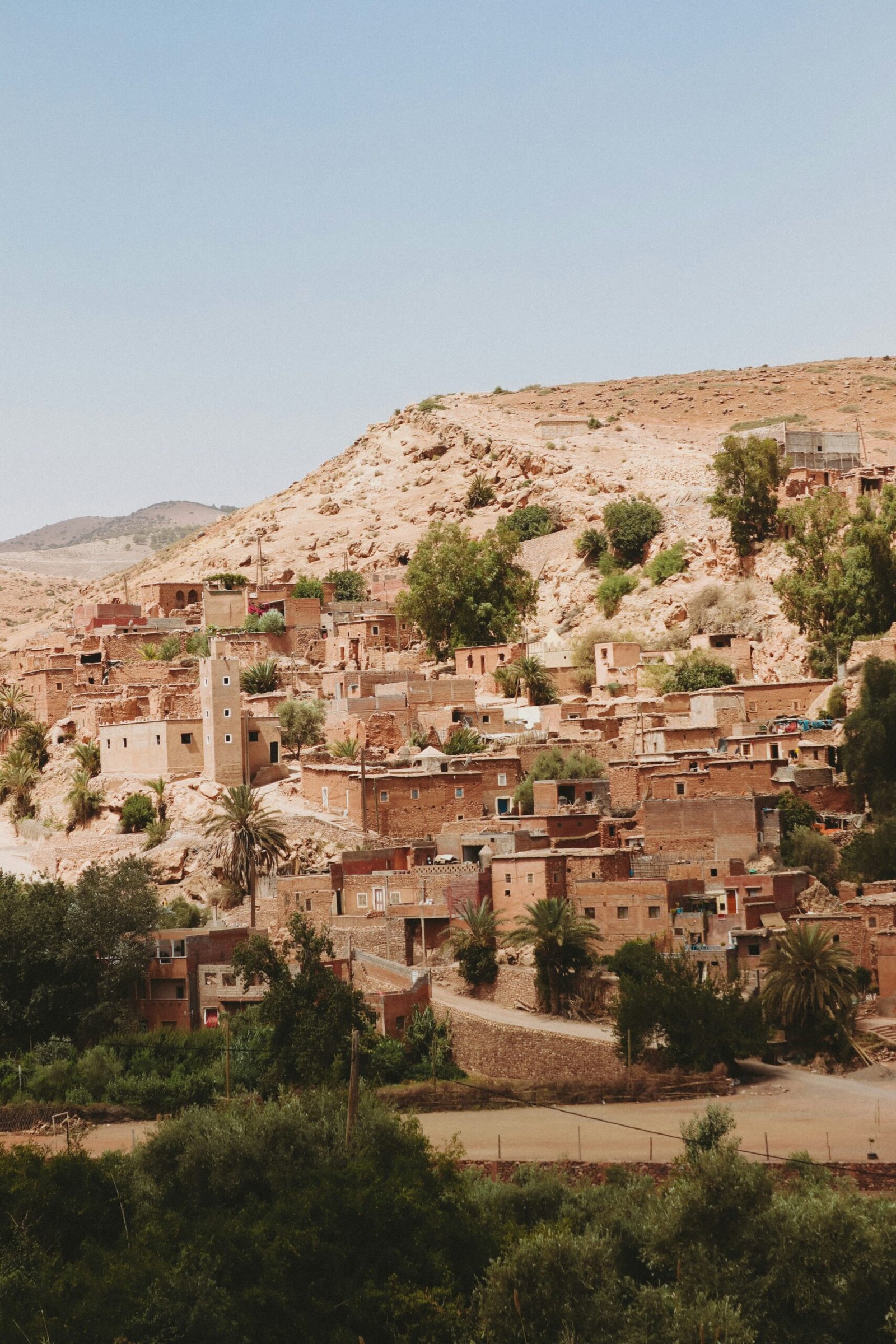 A traditional Berber village nestled in the arid High Atlas foothills of Morocco, featuring earthen architecture and palm trees, perfect for a secluded September wellness retreat.
