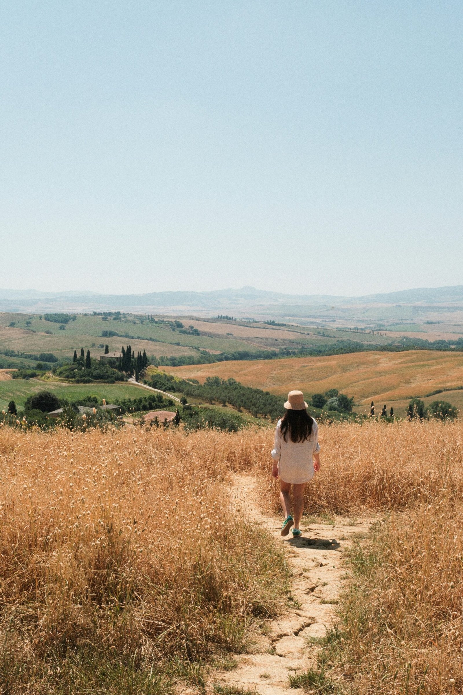 A woman walking through golden Tuscan fields, illustrating the power of mindful movement and releasing stress in nature.