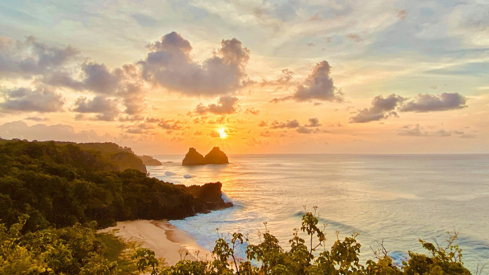 A dramatic sunset view from a rocky cliff overlooking the turquoise ocean in Bali, representing the serene atmosphere of an August 2026 peak season yoga retreat.