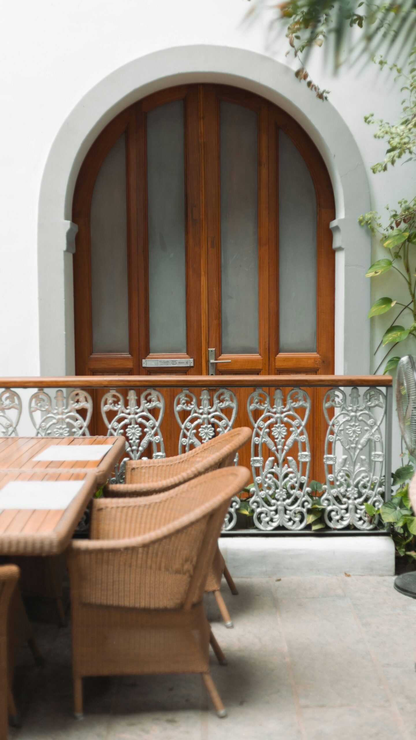 A serene outdoor patio in a Moroccan-style boutique hotel with woven chairs, a wooden table, and an arched doorway, perfect for an intimate October wellness retreat.