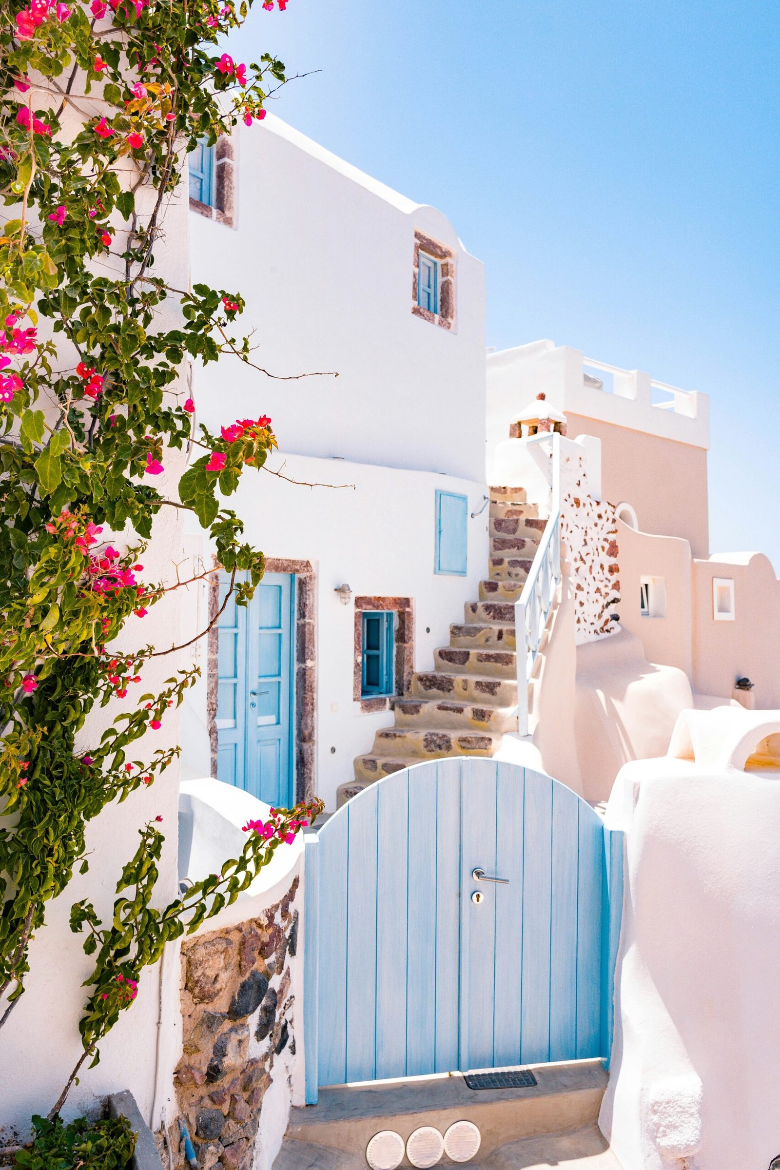 Blue gate at a Greek cottage entrance in Oia, Santorini, creating a quiet retreat arrival scene.