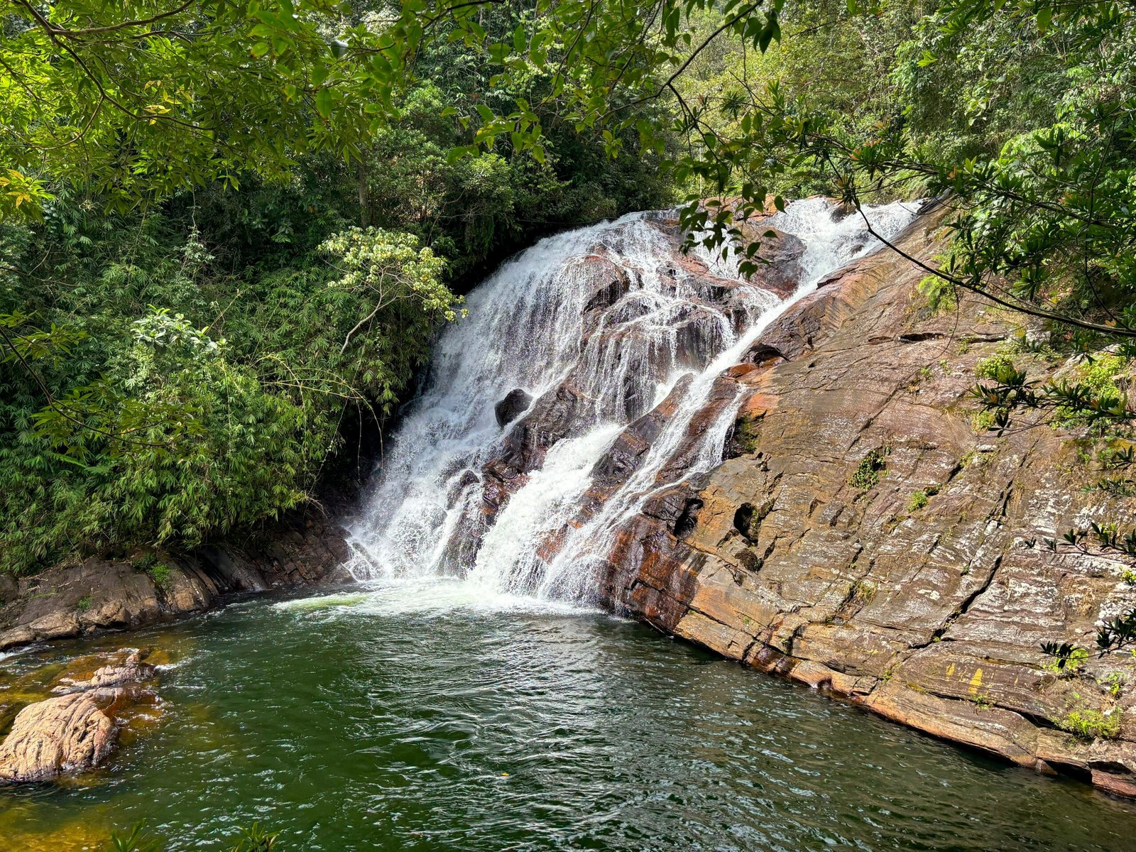 Brahmana Waterfall in Deniyaya surrounded by rainforest evoking the cleansing energy of an April ayurveda retreat.