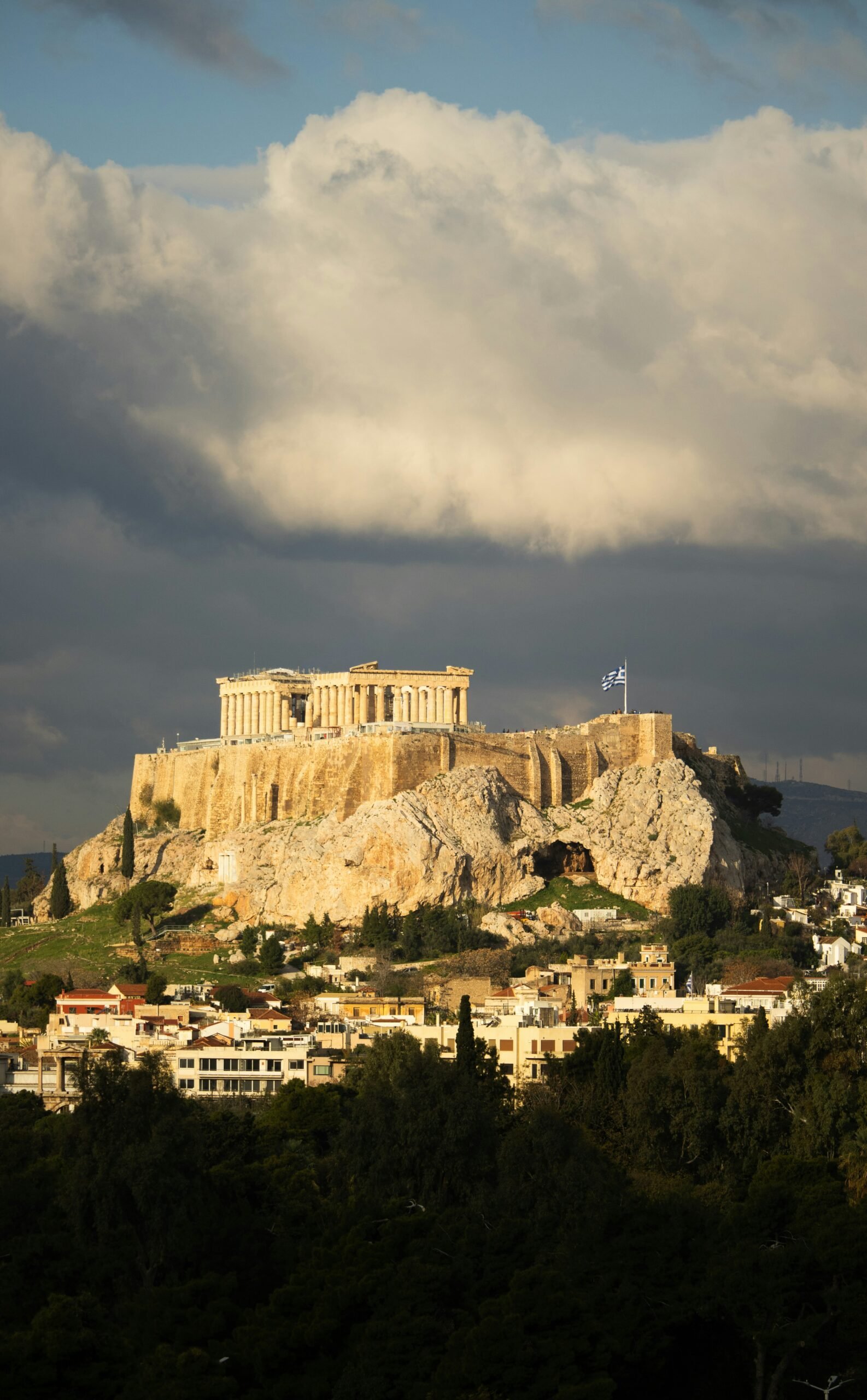 Acropolis of Athens beneath dramatic clouds, giving an urban Greece retreat a grounded and introspective mood.