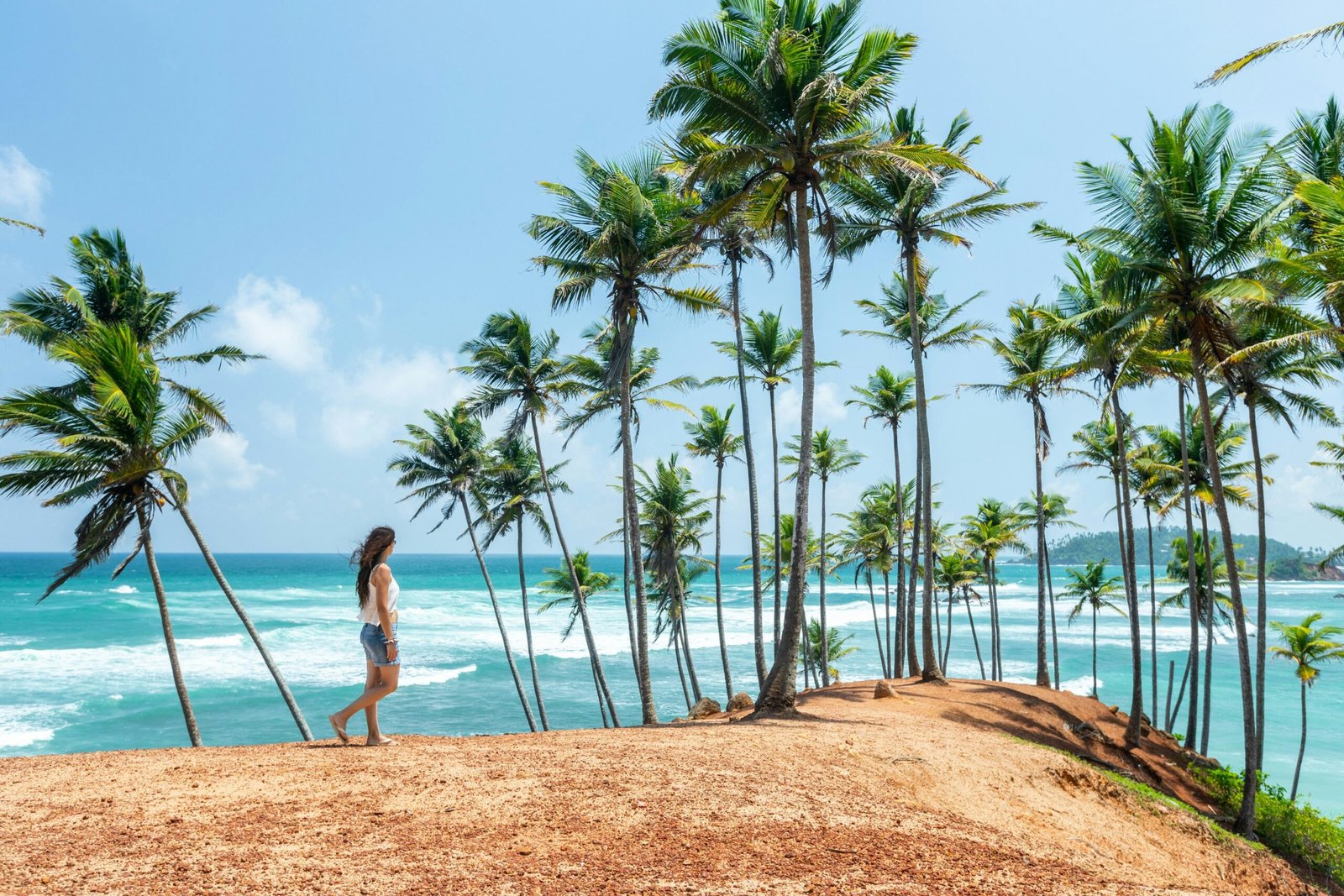 Woman walking along a palm-lined beach in Sri Lanka, capturing the calm and spacious feel of a seaside yoga retreat.