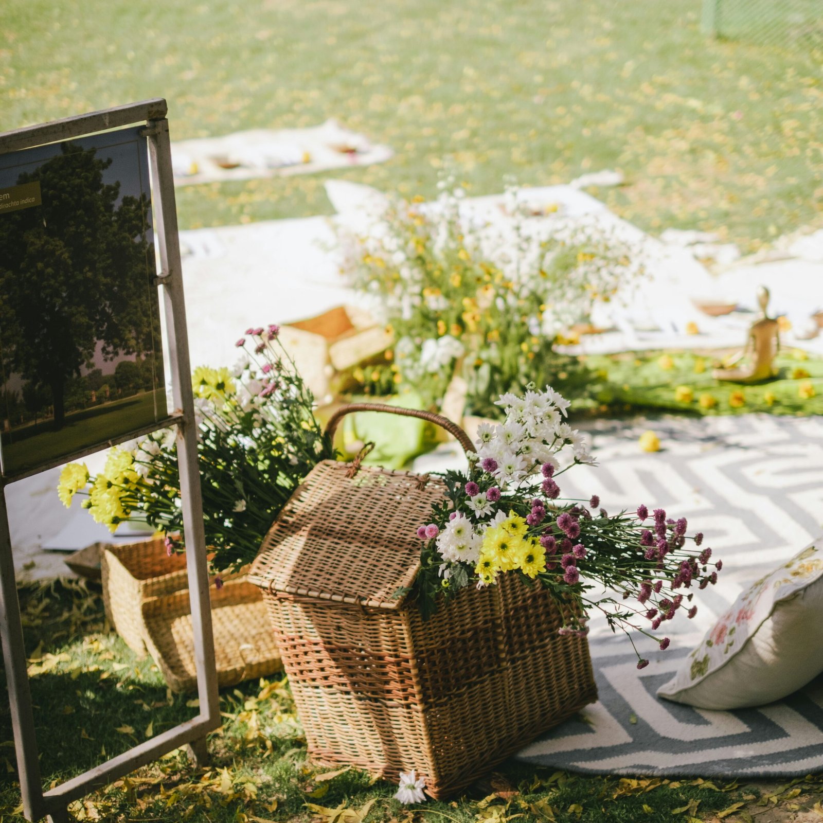 Wicker basket filled with flowers beside a mirror in a market-style display with a soft, natural feel.