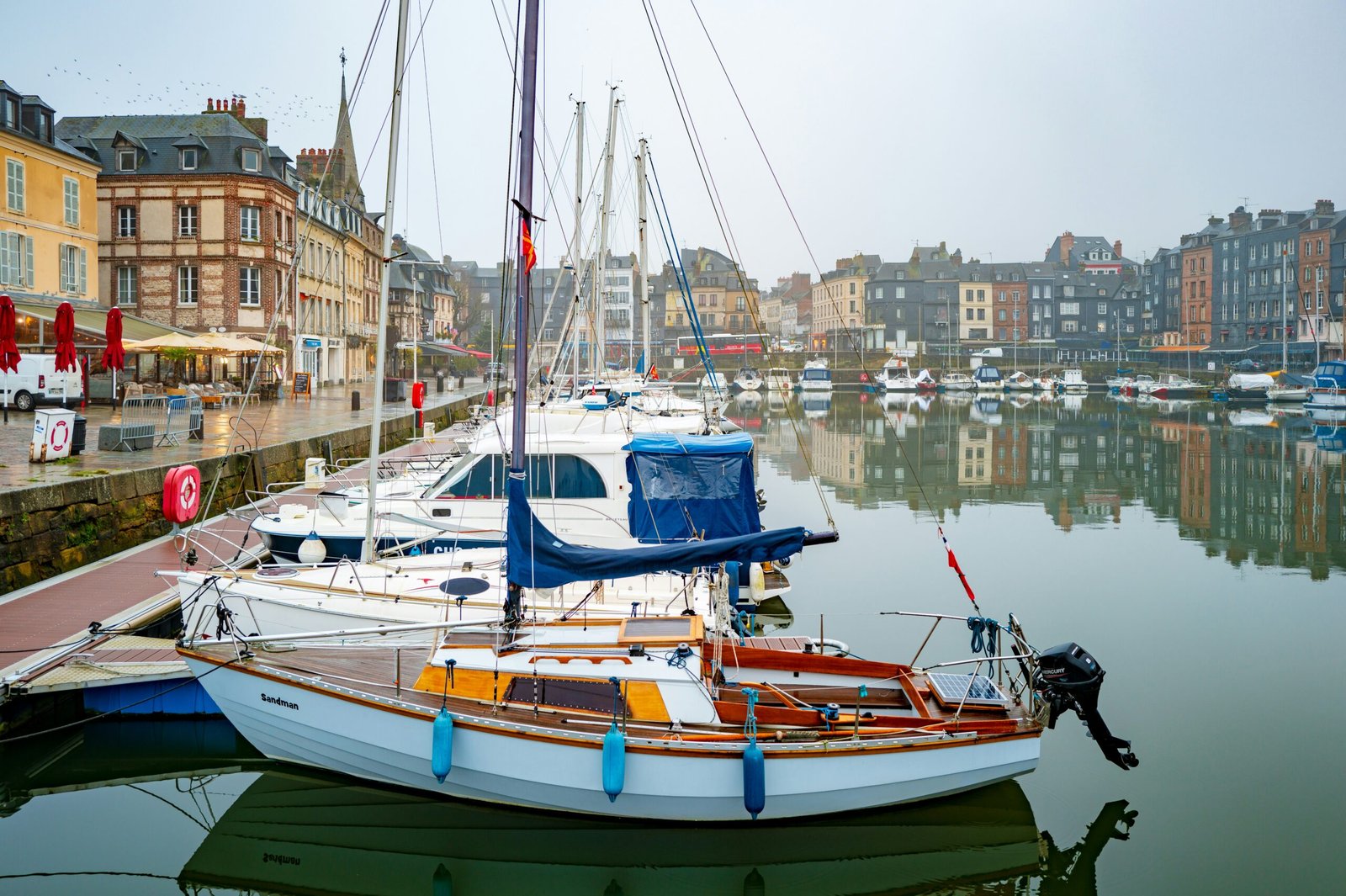Honfleur harbor with boats and historic waterfront buildings, bringing a relaxed summer atmosphere to a yoga retreat in France.