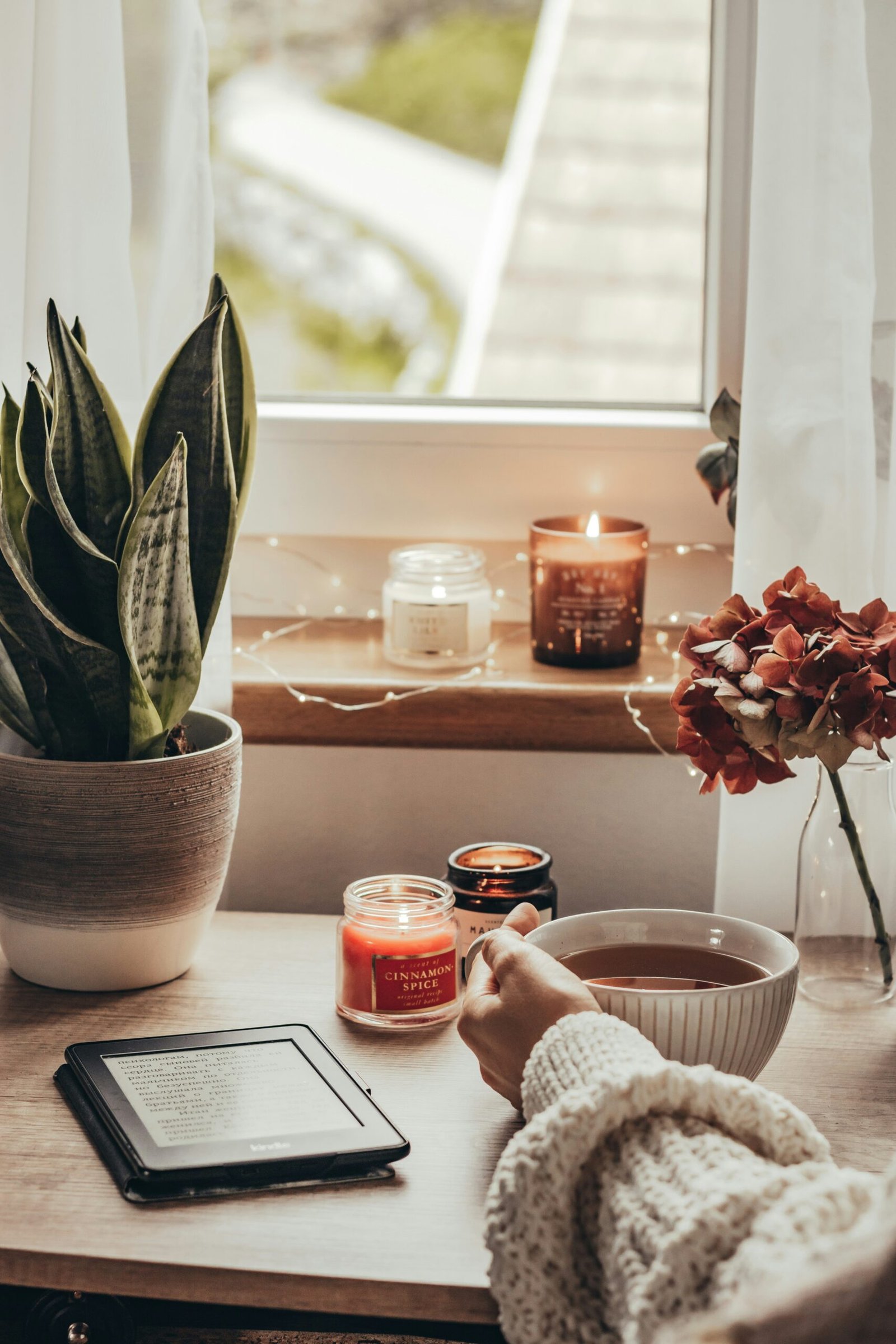 A cozy home sanctuary with a warm cup of tea and lit candles, representing the importance of creating a peaceful domestic environment after a wellness retreat.