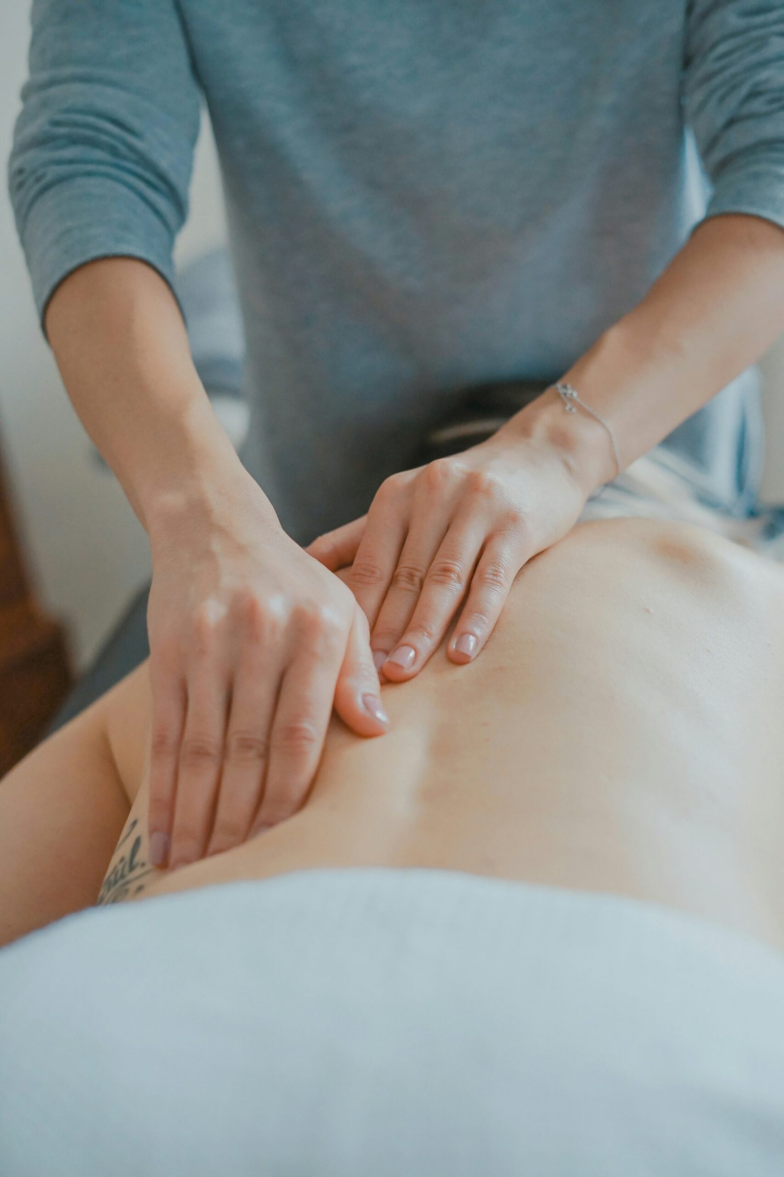 Therapist performing a relaxing body massage in a tranquil spa setting, reflecting the restorative treatments of an Ayurveda retreat.