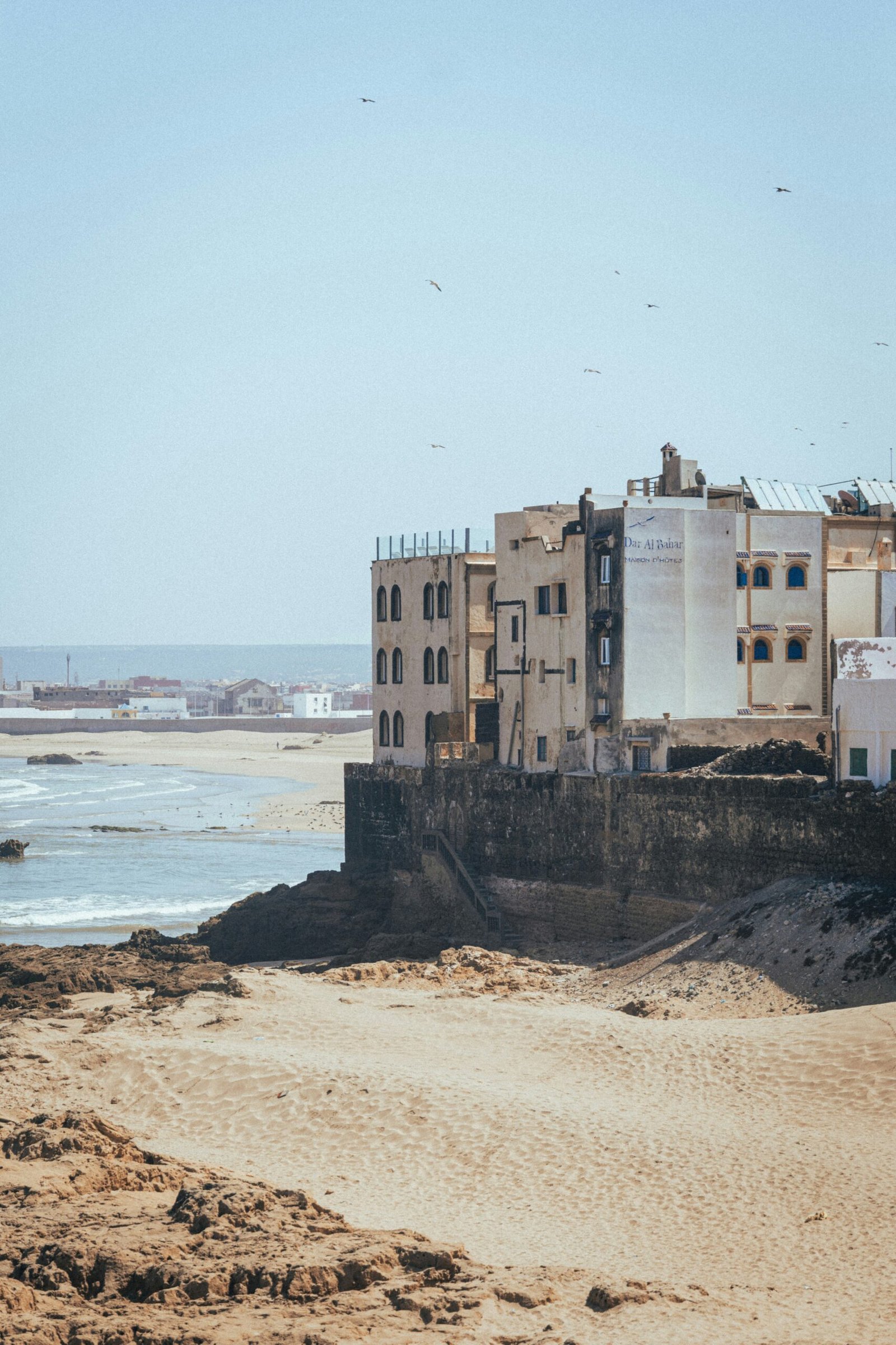 windswept essaouira beach beside old sea walls under pale autumn light