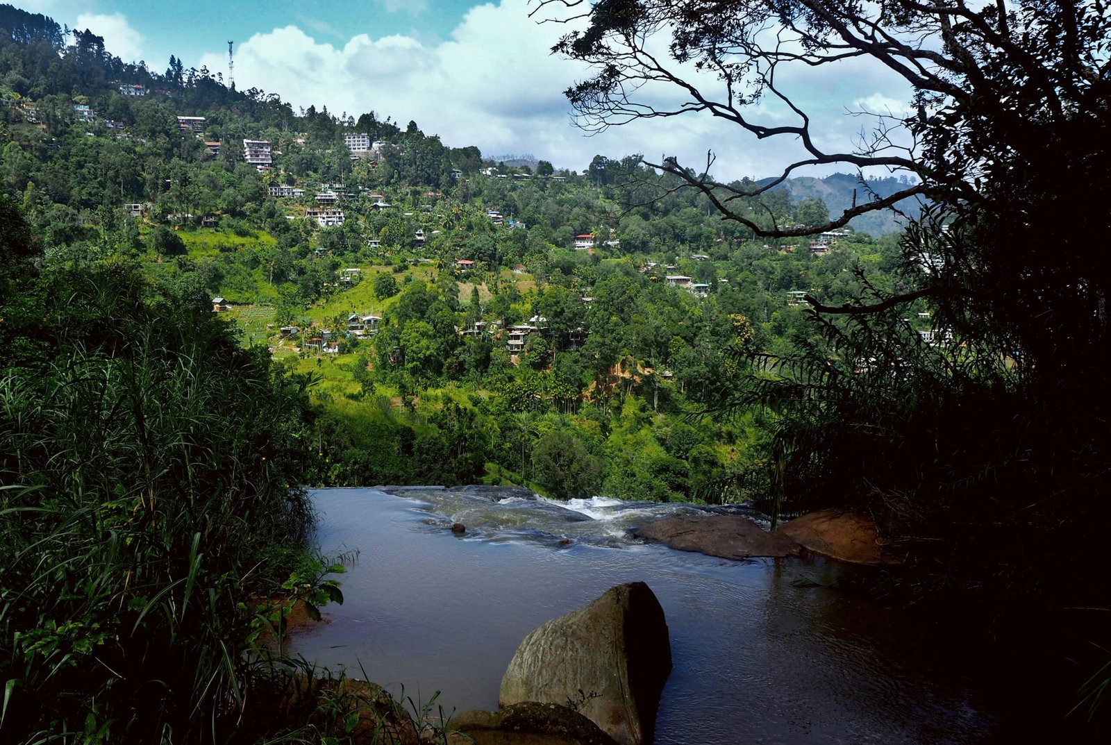Waterfall and hillside scenery in Ella capturing the humid green beauty of a May wellness retreat in Sri Lanka.