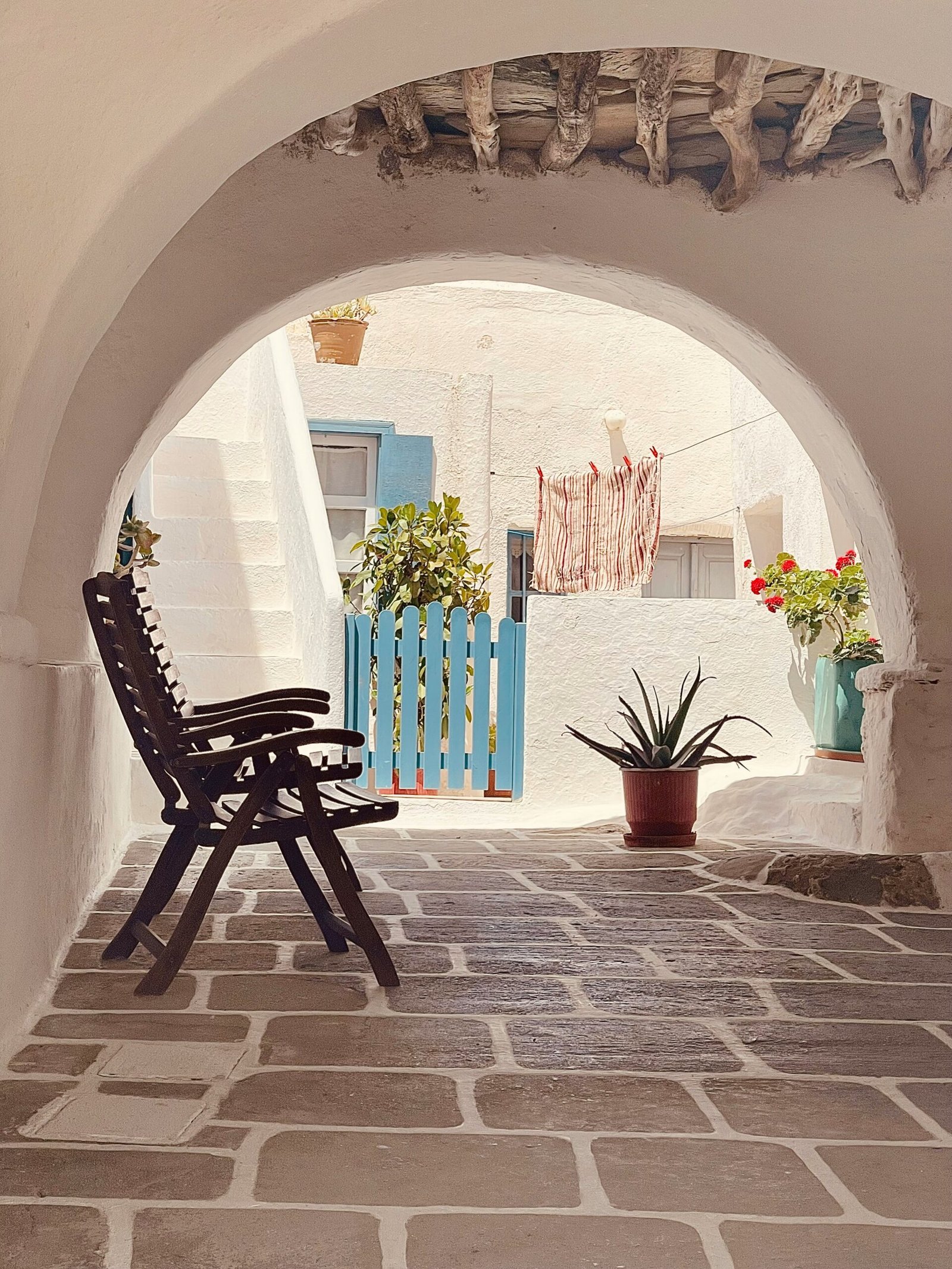 Sunny patio with potted plants in Folegandros, bringing a quiet island atmosphere to a restorative retreat in Greece.