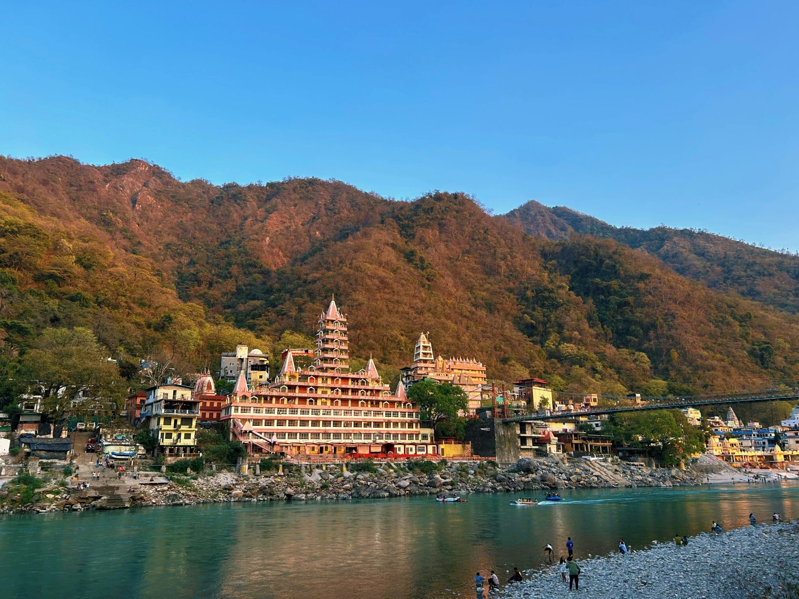 Rishikesh town and river framed by green hills, matching the pilgrimage and practice atmosphere of an autumn retreat in India