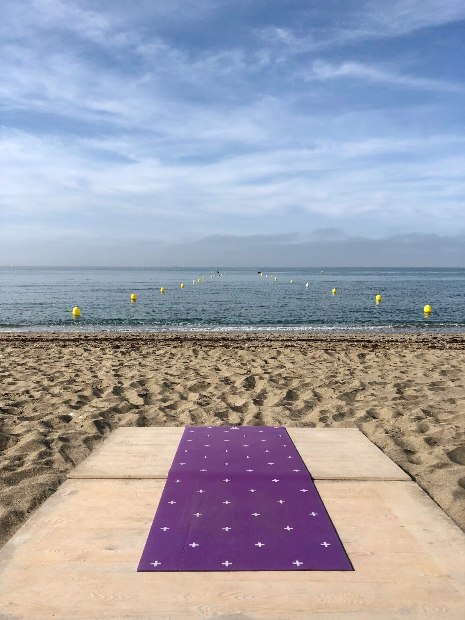A purple yoga mat rolled out on a wooden platform at a Portuguese beach resort, inviting travelers to experience the serene coastal wellness sanctuary of Europe.