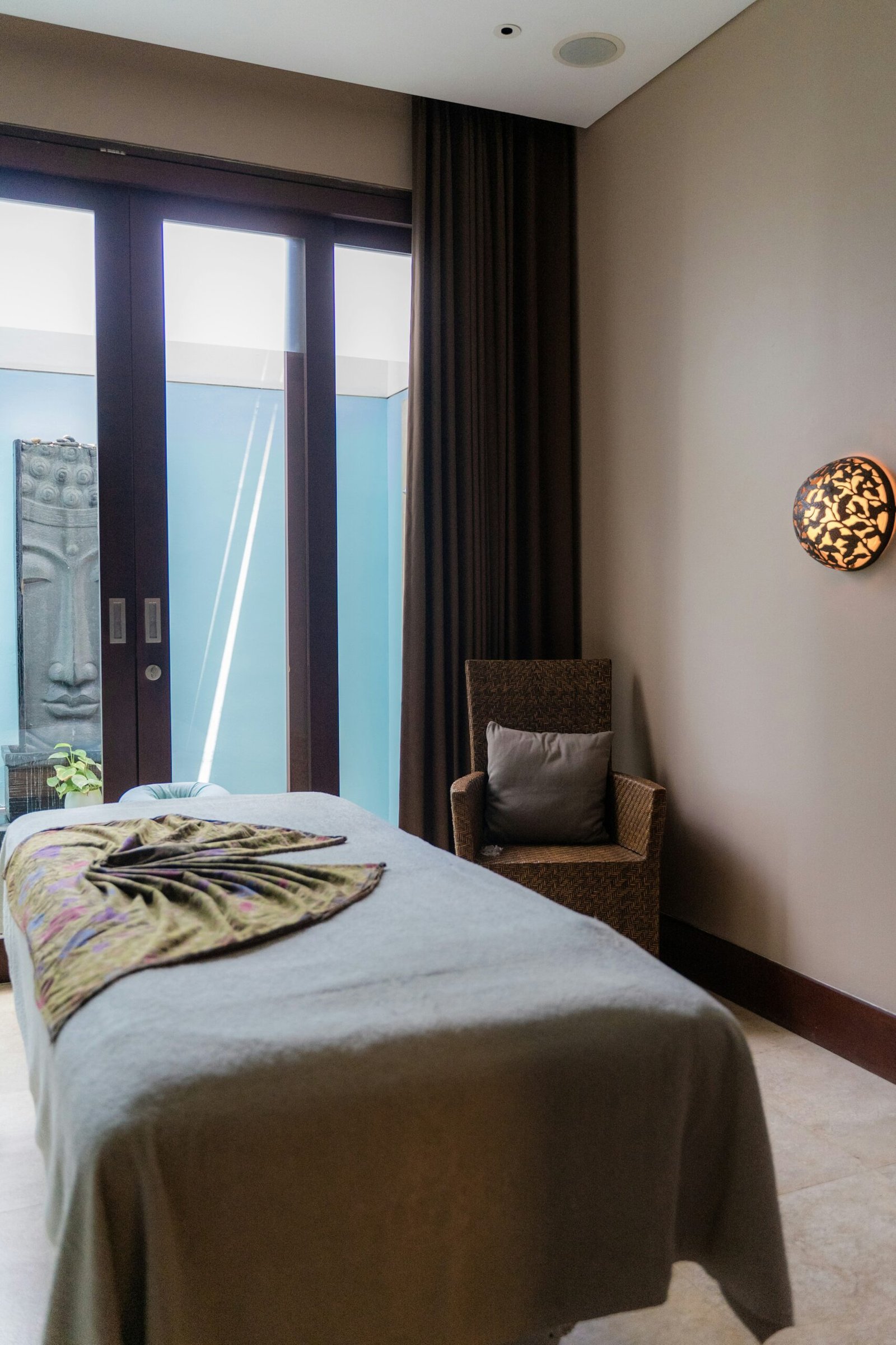 Massage room with a zebra-print cushion on a gray treatment bed in a calm spa setting.