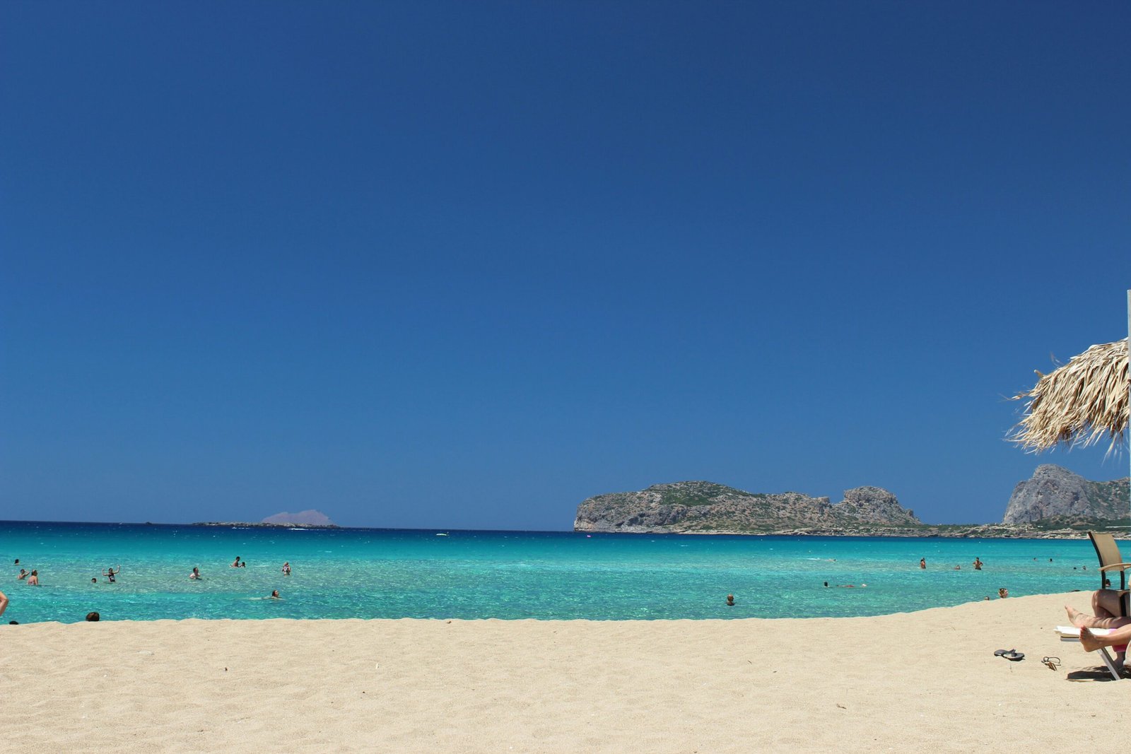 Seaside scene in Crete with sunlit sand and blue water, matching a calm spring retreat on a Greek island.
