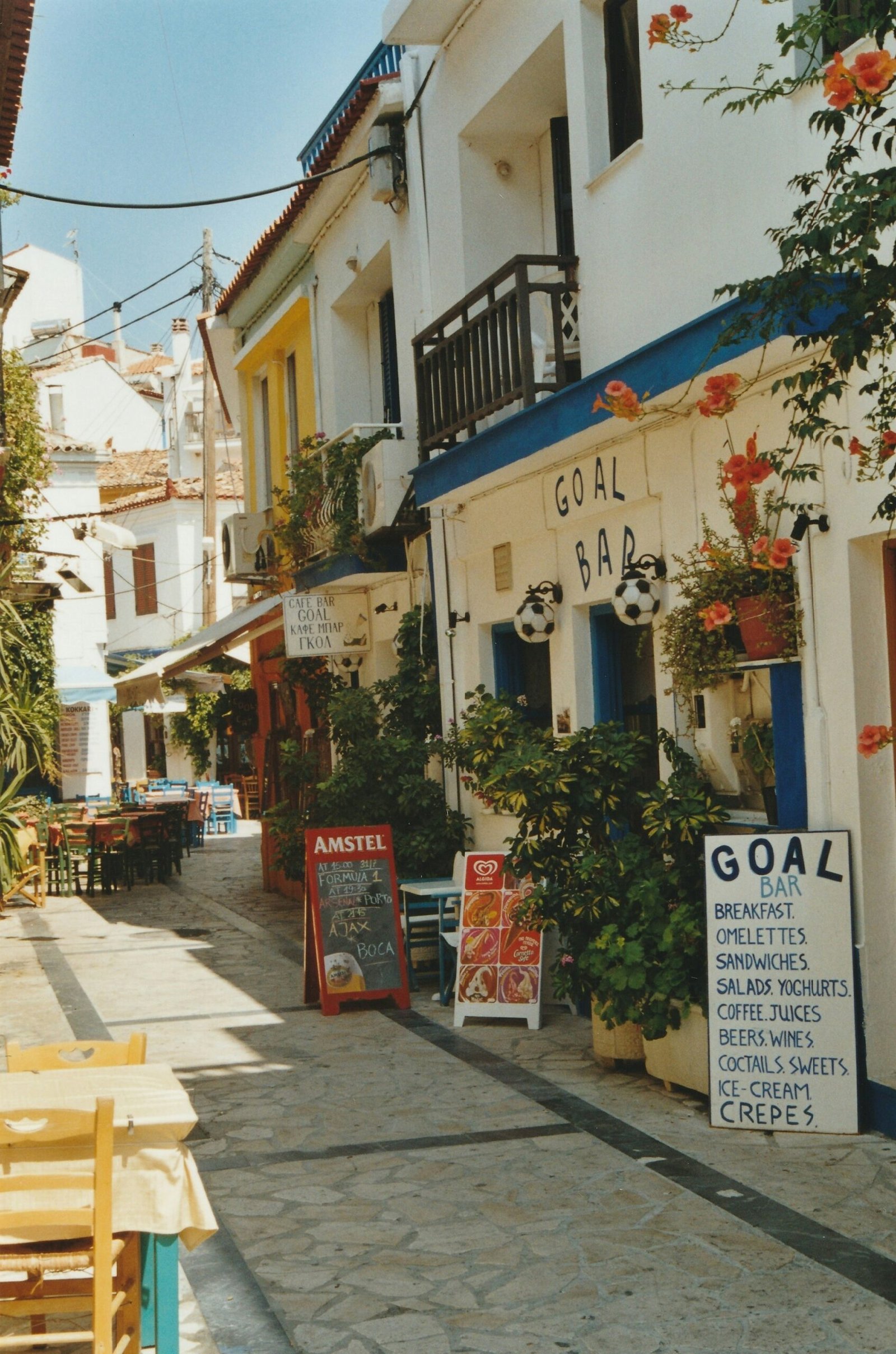 Quiet village street in Kokkari, Samos, with plants and shaded storefronts, creating a relaxed setting for a Greek retreat stay.