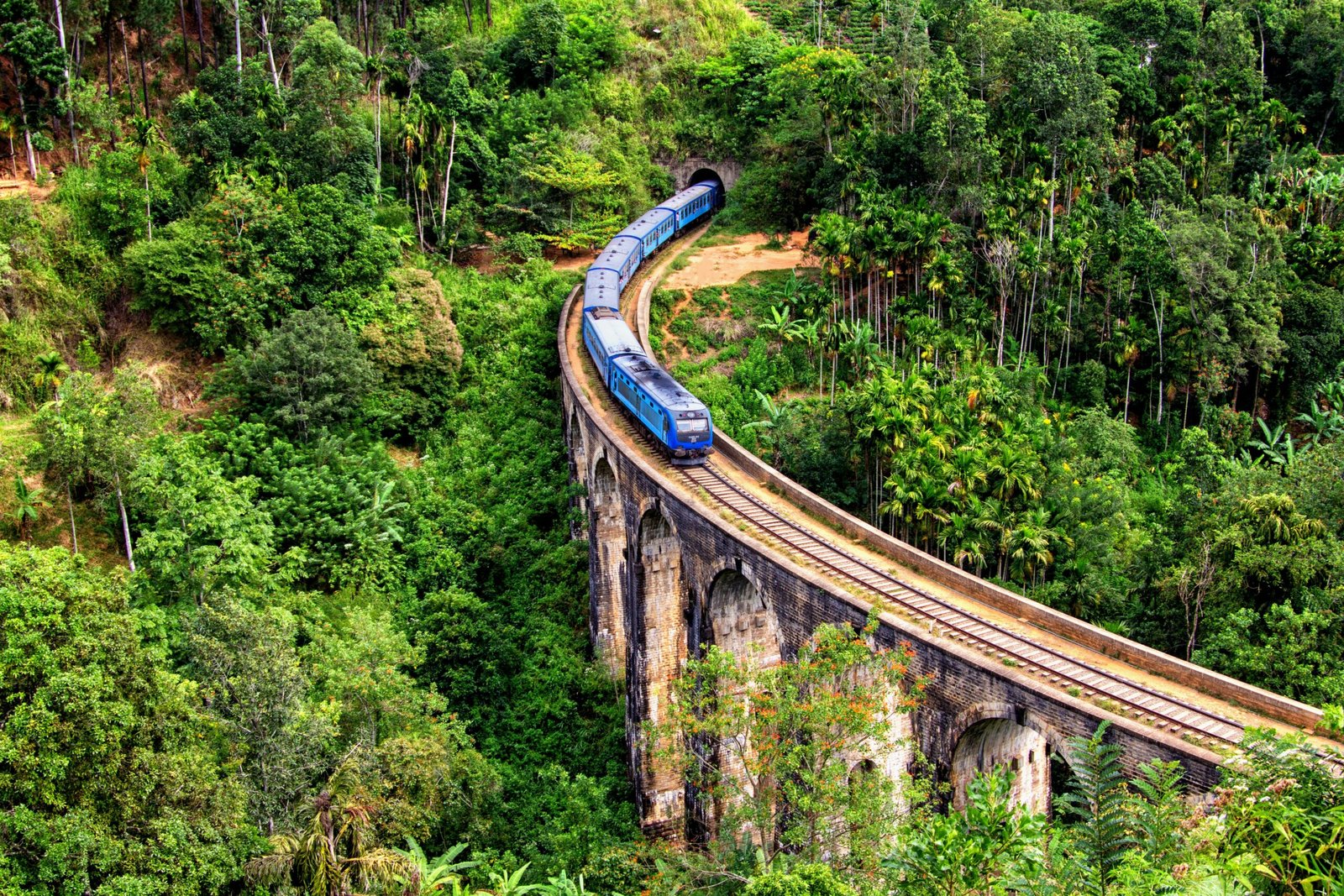 Blue train crossing Nine Arch Bridge in Ella, Sri Lanka, reflecting the scenic and grounding atmosphere of a hill-country yoga retreat.